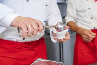 Person serves ice cream in a container with a scoop