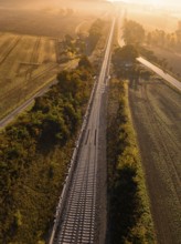 Aerial view of a landscape with railway tracks and fields in the warm autumn light of sunrise, a