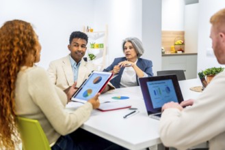 Multiethnic business professionals collaborating around a table, sharing insights from digital
