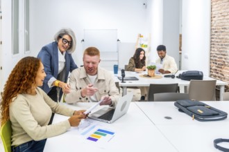 Diverse business people collaborating around a table in a modern office, discussing data and