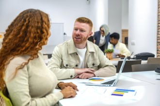 Diverse colleagues collaborate over charts and laptops in a modern coworking space, sharing ideas,