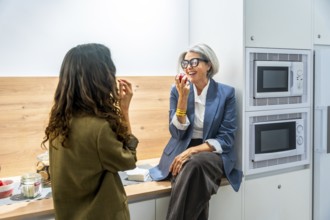 Two business women colleagues having a healthy snack, eating apples and laughing together while