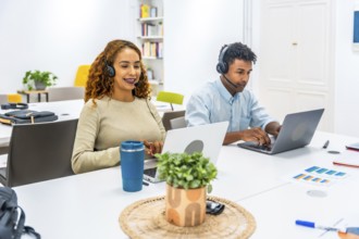Customer service representatives wearing headsets and working on laptops, connecting with clients