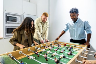 Diverse coworkers enjoying a friendly foosball game during a work break, fostering teamwork,