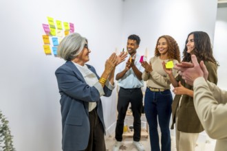 Diverse business people clapping hands in an office meeting room, celebrating a successful project