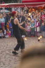 A fire-breather juggles in front of a colourful audience at a festival, Feuernacht, Sindelfingen,