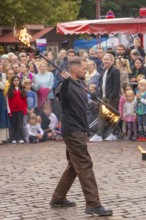 A juggling artist performs fire tricks in front of an interested audience, Feuernacht,