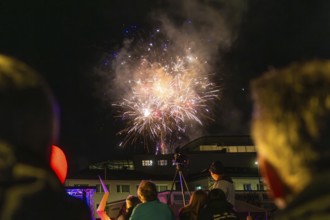 People marvelling at fireworks in the night sky above buildings, Fire Night, Sindelfingen, Germany