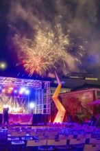 A colourful firework display over an illuminated stage at a night-time event, Fire Night,