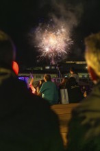 Group of spectators watching fireworks in the night sky above a building, Fire Night, Sindelfingen,