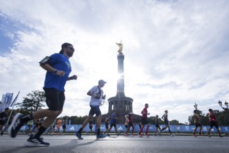 Runners run around the Victory Column against the backlight of the sun on the Great Star at the