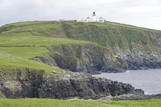 Lighthouse on a grassy cliff overlooking the sea under a cloudy sky, Sumburgh Head, Shetland