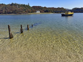 Clear lake surface with a yellow boat and wooden houses on the shore, Silver Sands of Morar, Morar,
