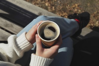 Top view of woman sitting on bench holding coffee cup in autumn setting. Generative ai, AI