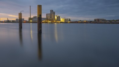 View across the Weser past dolphins to an industrial area in the evening light, Gröpelingen,
