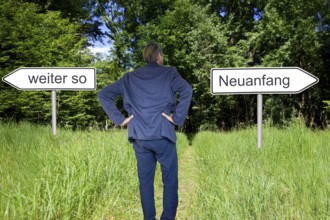 (Photomontage) Businessman stands in nature and has the choice between the direction CONTINUE AS IS