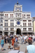 Venice, Italy - 3 September 2025: Tourists at the clock tower of San Marco on St Mark's Square in