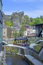 Tourists at restaurant along the river Ourthe and ruined castle in the city La Roche-en-Ardenne,