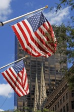 Waving USA flags, behind towers of St Patrick's Cathedral, Manhattan, New York City, USA