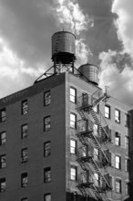 High-rise residential building with wooden water tanks on the roof, black and white, New York City,
