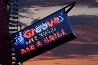 Illuminated advert in front of a bar, at dusk, New York City, USA