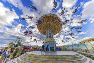 Chain carousel in motion in front of a white-blue sky, Theresienwiese, Oktoberfest, Munich, Upper
