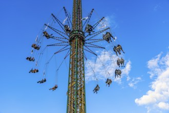 Oktoberfest attraction amusement ride Kettenflieger in front of a white-blue sky, Oktoberfest,