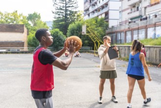 Young basketball player practicing shooting technique on outdoor court, receiving guidance from