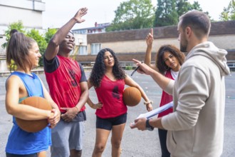 Basketball coach holding a clipboard, explaining game strategy while engaging with team players