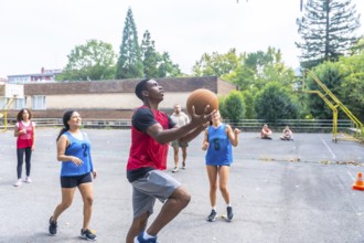 Group of diverse basketball players enjoying a lively game on an outdoor court, highlighting