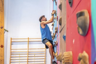 Young sportsman ascending a vibrant climbing wall, showcasing strength, agility, and intense focus