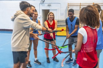Floorball players gathering their sticks in a circle before a match, smiling and displaying