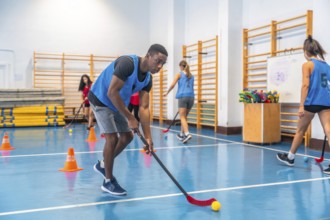 Focused young athlete dribbling floorball ball in gym, practicing stick handling skills with