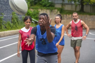 Rugby player wearing a blue training bib is catching a ball during practice, surrounded by