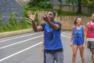 Young male athlete wearing a blue training bib catching a rugby ball during practice, with his
