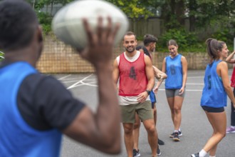 Group of athletes in sportswear engaging in passing drills while training on an outdoor court,