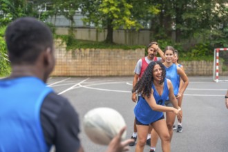 Diverse group of multi ethnic rugby players enjoying training on an outdoor court, passing the ball