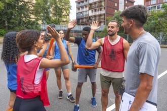 Multi ethnic baseball team giving high fives to their coach after winning a game, celebrating their