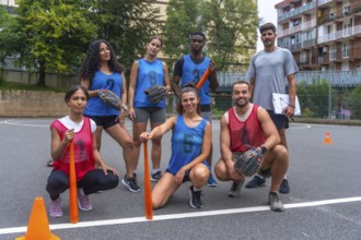 Multiethnic baseball team posing with their coach on the field before a game, holding bats, gloves,