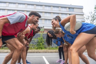 Two rugby teams, one in red and one in blue, are facing each other and smiling before a match, with