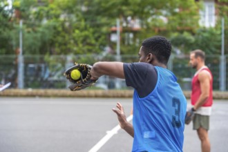 Young baseball player wearing a blue uniform is pitching the ball with his glove during a game on