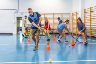 Group of athletes engaged in an intense floorball training session, skillfully dribbling the ball
