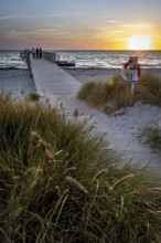 Sunset on the beach with wooden jetty and lifebuoy on a post, calm ocean in the background, Kobaek