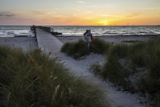 Evening beach dunes and lonely passenger pier at sunset, peaceful sea waves, Kobaek Strand,