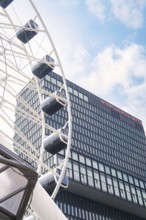 Modern Ferris wheel near a glass building under a blue sky, Werksviertel Munich, Munich, Germany