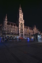 Historic building at night with lighting, people walking around, Munich, Germany