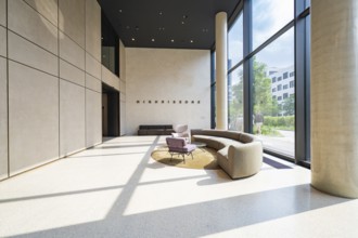 Elegant lobby with plenty of sunlight, modern furniture and a large glass wall, Munich, Germany
