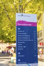 Urban signpost with various destinations, surrounded by trees under a sunny sky, Sindelfingen,