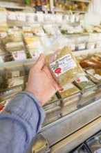 Someone holding a packet of dried rosemary in front of a spice rack, Sindelfingen, Böblingen