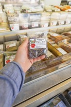 Hand holding a package in front of a shelf with food in a supermarket, Sindelfingen, district of
